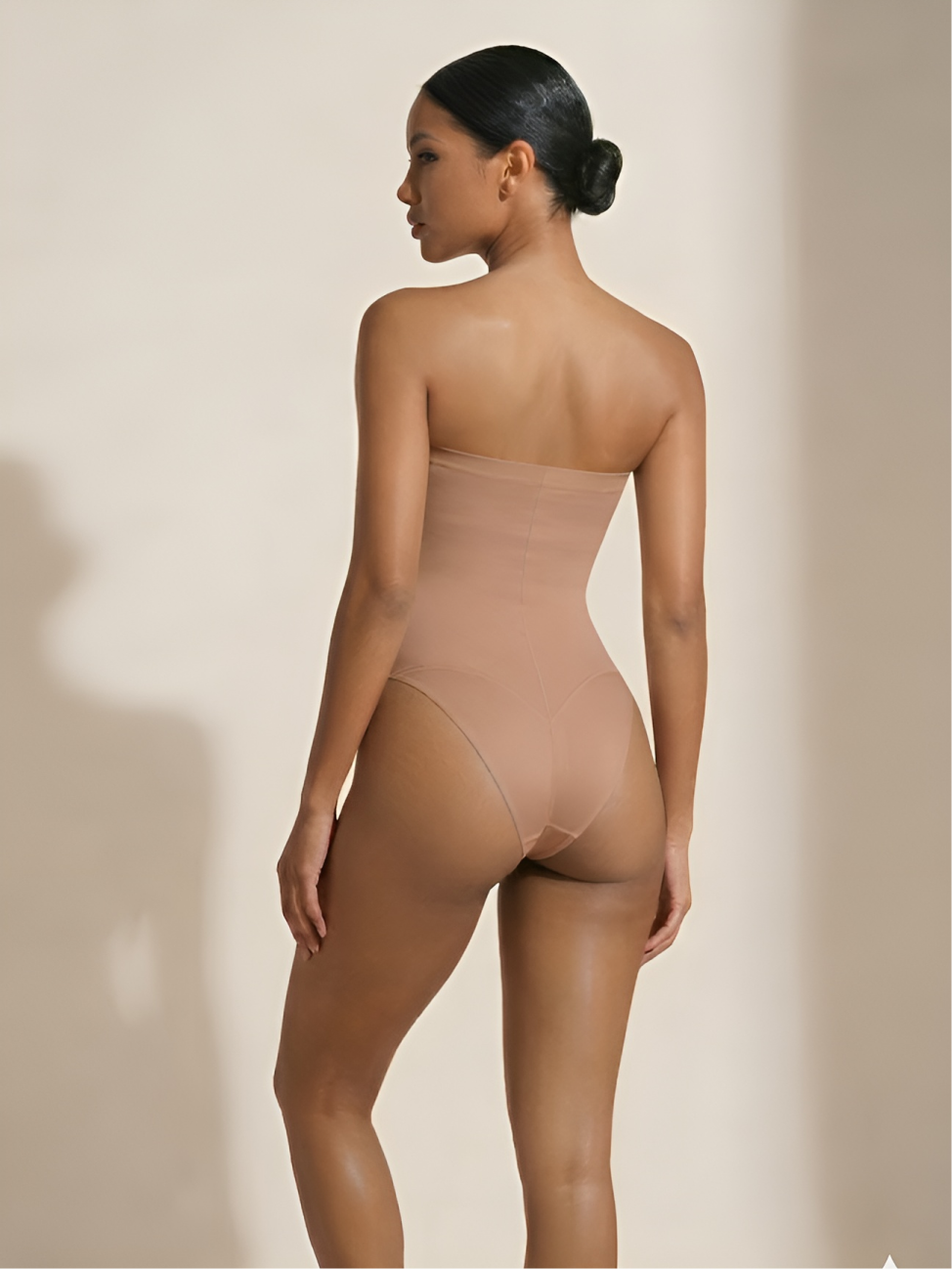 Back angled view of nude strapless thong shaper with smooth waist and hip shaping